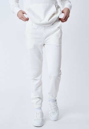 White jogger pants made of soft material, featuring an elastic waistband, cuffed ankles, and a small embroidered logo on the side.