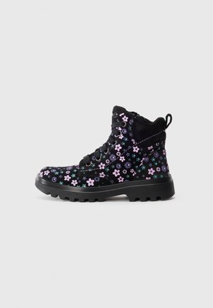 Bottines noires avec un motif floral rose et vert, fabriquées en tissu doux avec une finition texturée et une semelle en caoutchouc robuste.