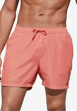 Shorts de bain corail en tissu léger avec une taille élastique et un cordon de serrage réglable. Présentent une texture lisse et un design décontracté.
