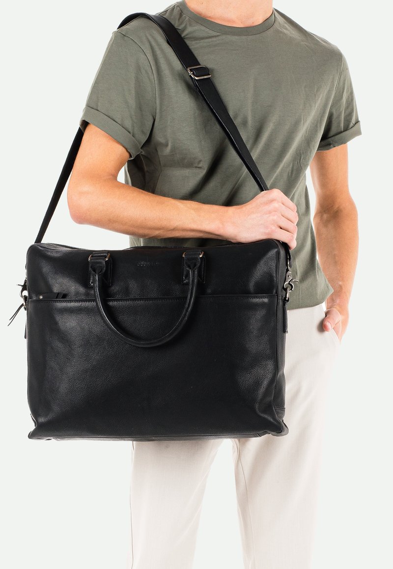 Schwarze Ledertasche mit doppelten Griffen und einem abnehmbaren Schultergurt. Verfügt über eine vordere Reißverschlusstasche und eine strukturierte Oberfläche.