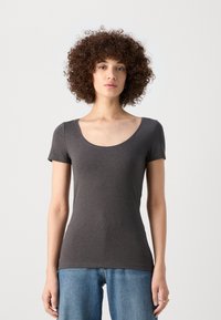 Grå kortärmad t-shirt med rund halsringning, figurnära design, tillverkad av ett mjukt material. Matchad med högmidjade blå denimjeans.