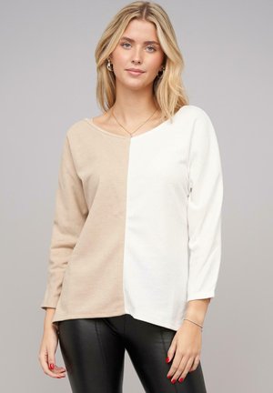 Cream and beige color-block long-sleeve top with a wide neckline. Soft fabric, relaxed fit, and side seam detailing.