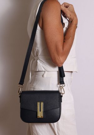 Schwarze Leder-Crossbody-Tasche mit strukturierter Oberfläche, Hardware in Goldton und Klappenverschluss. Verstellbarer Riemen an der Tasche befestigt.