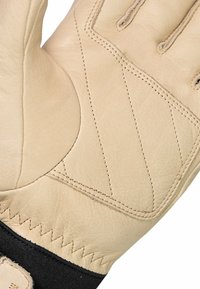 Beige leren handschoen met een gladde textuur, voorzien van diagonale stikdetails en een zwarte polswatch voor extra ondersteuning.