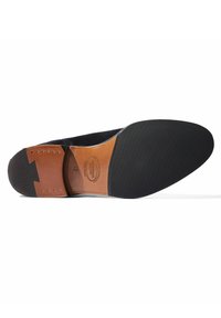 Suela de zapato de ante negro con una plantilla de cuero, logo en relieve y una suela exterior de goma texturizada para mayor agarre. Presenta remaches decorativos.