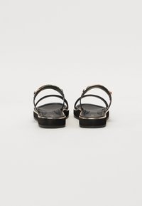 Mustad mustad sandaalid metallaktsentidega, kahekordsete rihmade ja pehme taldiga. Sile tekstuur ja minimalistik disain.