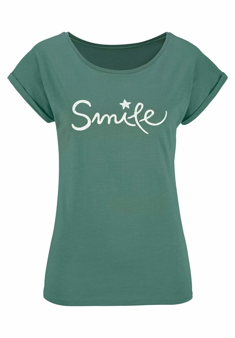 Zaļa T-krekls ar mīkstu tekstūru, noapaļotu apkakli, sarullētām piedurknēm un baltu "Smile" tekstu ar zvaigznītes akcentu.