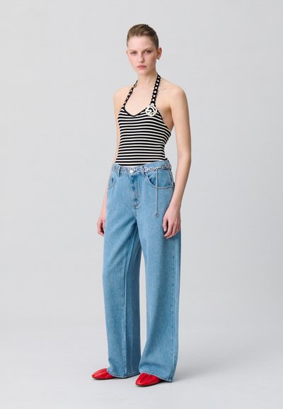 Top halter rayado con escote en V, combinado con jeans de pierna ancha de color azul claro. El calzado incluye bailarinas rojas con punta. Detalle de cinturón de cadena plateada incluido.