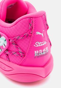 Spilgti rozā sporta apavi ar sieta un sintētisko materiālu, ar grafiskām akcentiem, teksturētām auklām un zīmolotiem papēža dizainiem.