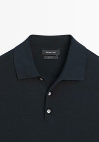 Sort bomulds polo-shirt med kort krave og tre hvide knapper, mærket Massimo Dutti, fremstillet i Kina.
