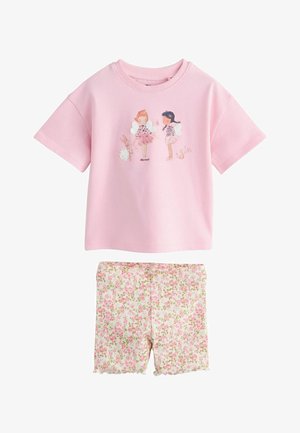 Roza top s kratkim rukavima s printom vile i životinja u kombinaciji s bijelim rebrastim šorcima s ružičastim cvjetnim uzorkom i valovitim rubovima.