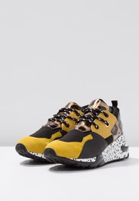 Herresneakers i sort, gul og leopardprint. Indeholder mesh, ruskind og teksturerede materialer. Klodsede såler med et plettet mønster.