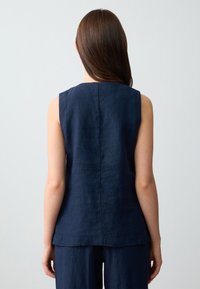 Top senza maniche in lino blu navy con taglio dritto, caratterizzato da una cucitura posteriore e un orlo leggermente curvo. Tessuto morbido e design minimalista.