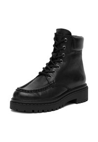 Fekete bőr bokacsizma párnázott gallérral, vastag talppal, mokaszin orral és fekete fűzőkkel, amelyek fém szemeken keresztül fűzöttek.