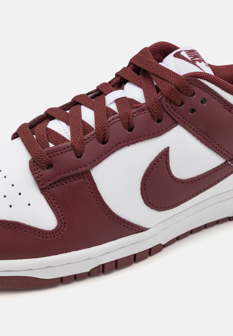 Zapatillas de cuero blancas y burdeos con acentos texturizados, puntera perforada, cordones burdeos planos y una entresuela blanca, con un logo en la lengüeta.