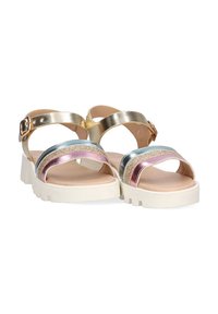Sandalias metálicas doradas con una suela blanca gruesa. Presentan correas coloridas y brillantes en azul, rosa y púrpura. Hebilla ajustable en el tobillo.