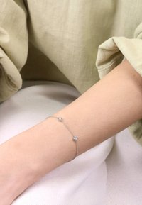 Silver chain bracelet featuring three clear, square gemstones set at intervals. Smooth texture with a minimalist design.
