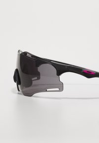 Czarne sportowe okulary przeciwsłoneczne z dużą, owładującą soczewką, z ciemnym gradientem, regulowanymi noskami oraz różowym akcentem na zauszniku.
