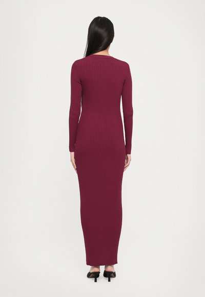 Long-sleeve burgundy ribbed dress with a form-fitting silhouette, reaching the ankles, featuring a round neckline and minimal detailing.