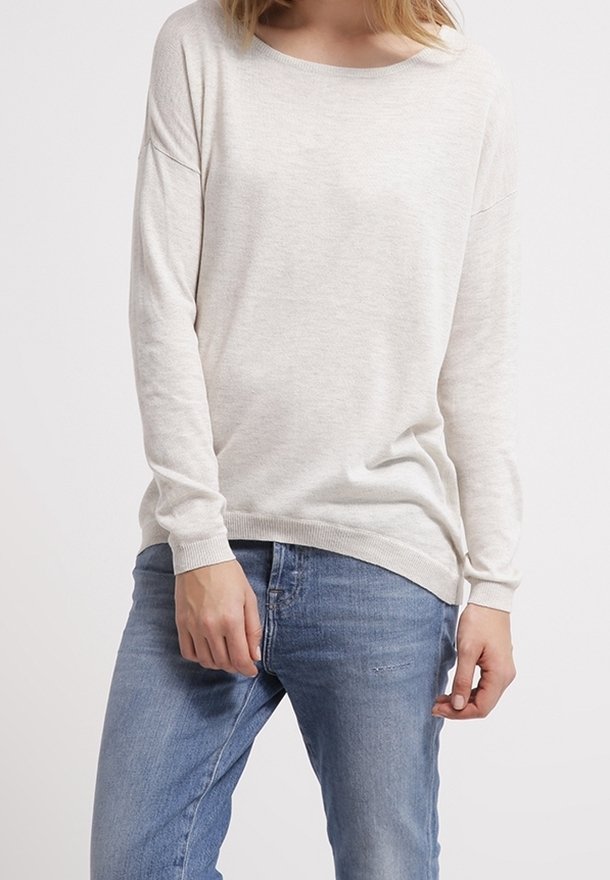 Ljusbeige långärmad tröja med rund halsringning. Har en mjuk textur och ribbade manschetter, ihop med blå denimjeans.