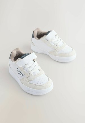 Biele tenisky s textúrovaným semišovým a koženým povrchom, vybavené suchým zipsom, šnurovaním a perforovaným detailom na špičke.