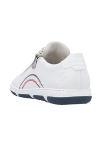 Baskets blanches avec une fermeture éclair, présentant un embout texturé et un motif de vagues rouge et noir cousu sur le côté. Semelle extérieure en caoutchouc visible.