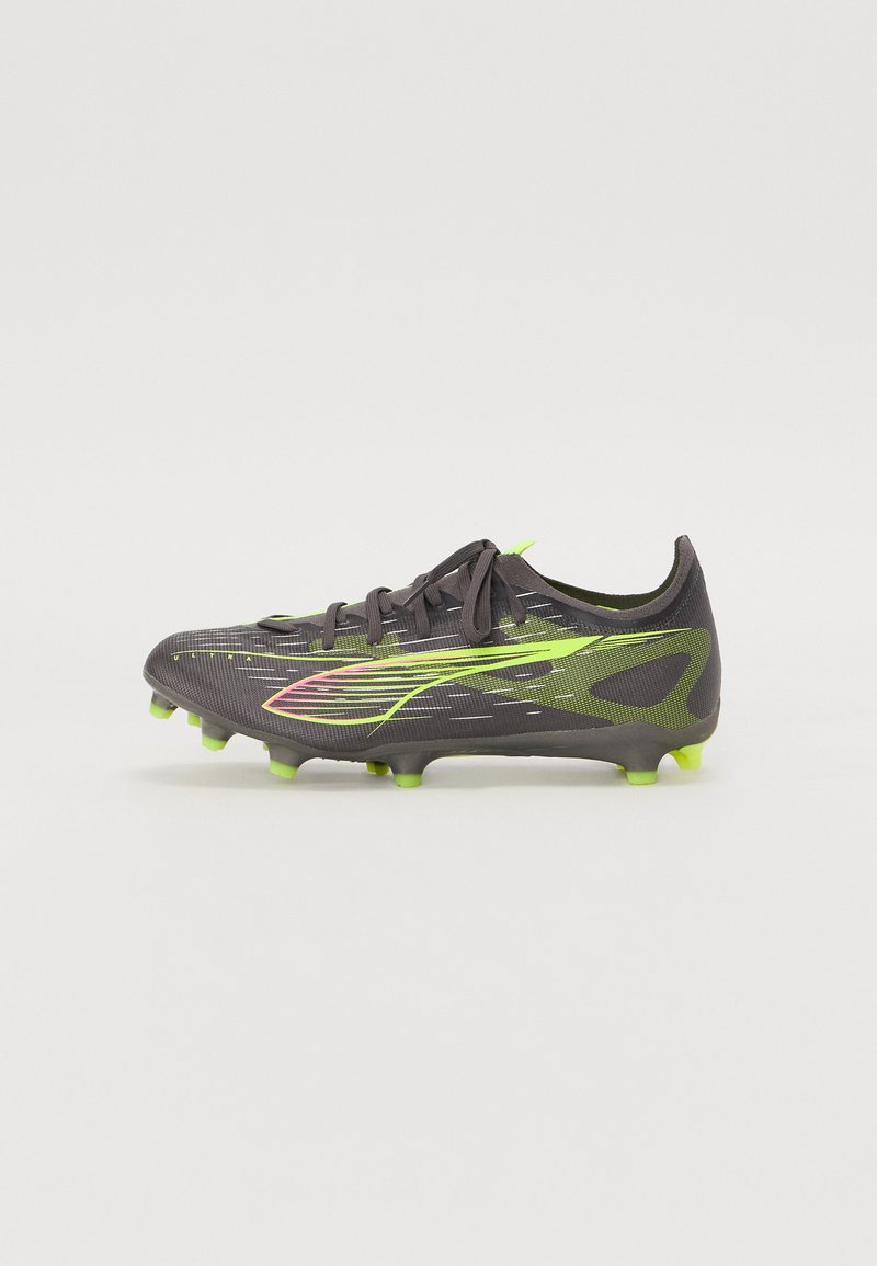Botas de fútbol negras con acentos en verde y rosa, material superior texturizado, cierre de cordones y suela con clavos para tracción en superficies de hierba.