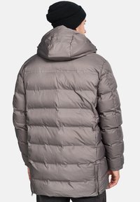 Chaqueta de plumas gris con capucha, que presenta un diseño acolchado, tejido texturizado y aberturas laterales con cremallera para un ajuste personalizado.