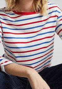 Camicia bianca con righe orizzontali rosse e blu, colletto rotondo e maniche a tre quarti. Il tessuto sembra morbido e con una superficie liscia.