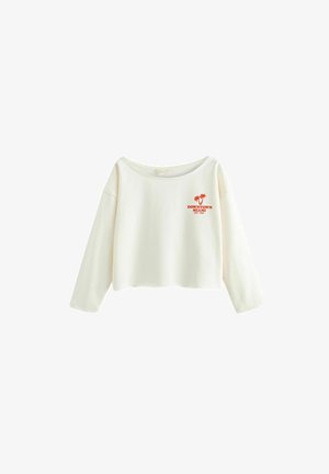Person trägt ein weißes Sweatshirt mit schulterfreiem Ausschnitt mit dem Schriftzug „Downtown Miami“ und Palmen-Grafik, kombiniert mit schwarzen Biker-Shorts.
