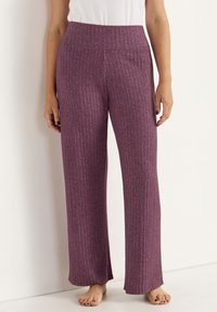 Paarse geribbelde wijde broek met een textuurstof en een hoge elastische tailleband. Het zachte materiaal valt soepel tot aan de enkels.