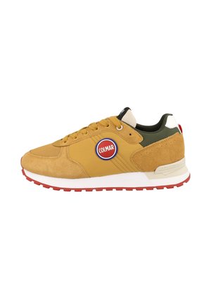 Zapatilla deportiva para hombre en amarillo mostaza con detalles en ante y malla, con un logo de Colmar rojo y blanco en el lateral y una suela de goma roja.