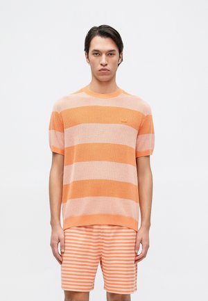 Pull en tricot rayé orange à manches courtes, avec un col rond et un motif texturé. Assorti à un short rayé.