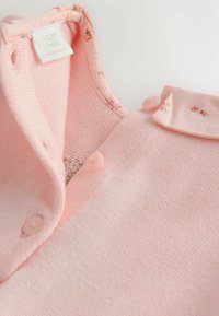 Miękki różowy kardigan dla niemowląt z małymi guzikami i kołnierzykiem w kwiatowy wzór, metka głosi "NEXT baby made in India."