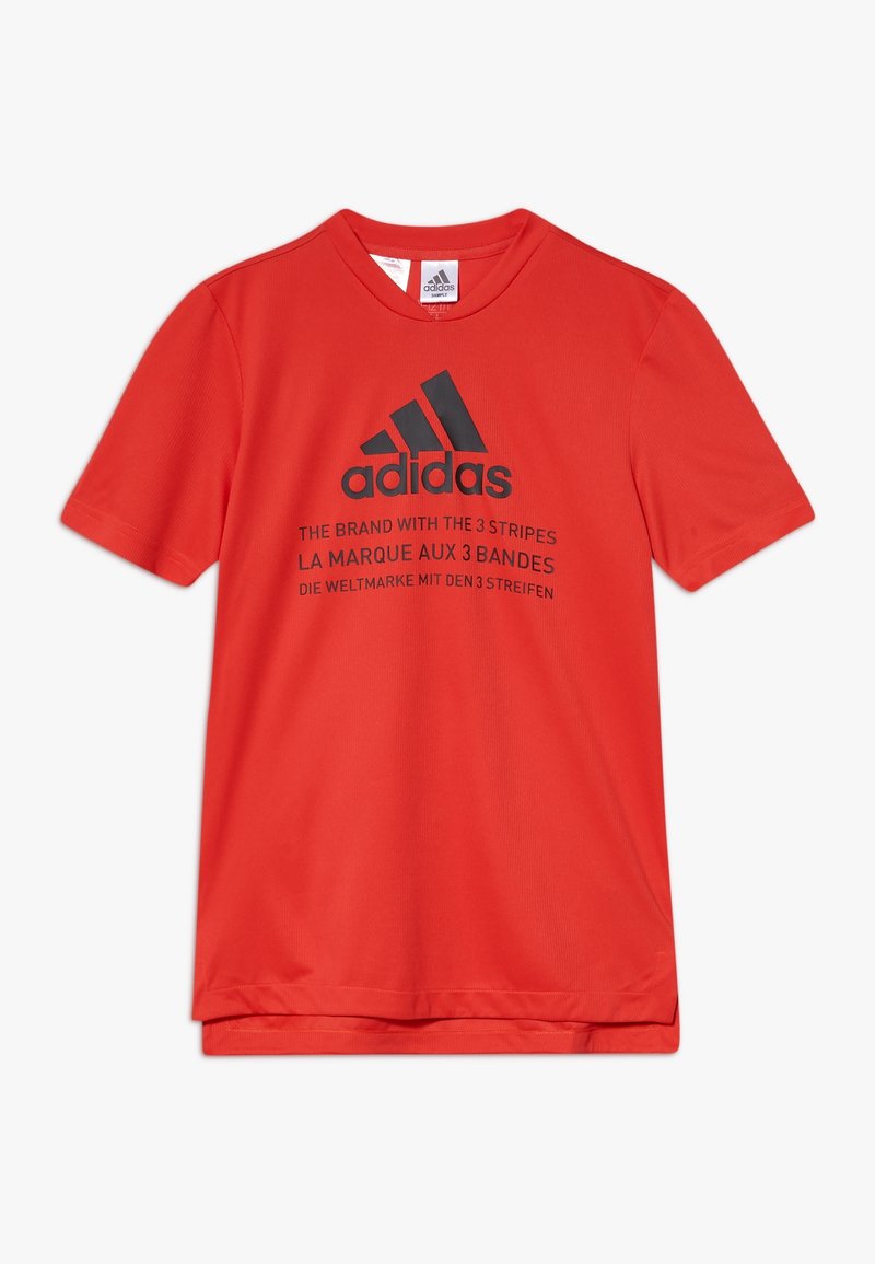 Červené sportovní tričko s krátkým rukávem značky Adidas s černým logem a vícejazyčným nápisem propagujícím tři pruhy značky na přední straně.