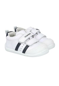 Zapatos infantiles blancos con la punta texturizada, que cuentan con dos franjas azul marino, correas de Velcro y un interior acolchado.