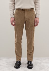 Cordhosen in hellbraun mit vertikal gerippter Textur. Kombiniert mit einem cremefarbenen Pullover und schwarzen Loafers, mit klassischer Passform und Taschen.