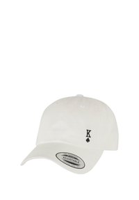 Hvit bomulls baseballcaps med justerbar stropp, med en svart "K" og spade-logo på fronten. Flat skygge med ventilasjonshull.