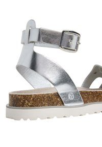 Silverfärgade klacksandaler med en spännen ankelrem, kork-mellansula och vit gummiyttersula. Har en slät metallic läderfinish.