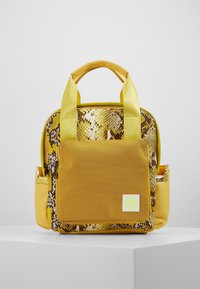 Mochila amarilla con un reverso de patrón de serpiente, que cuenta con un bolsillo frontal, dos asas superiores y una textura suave.