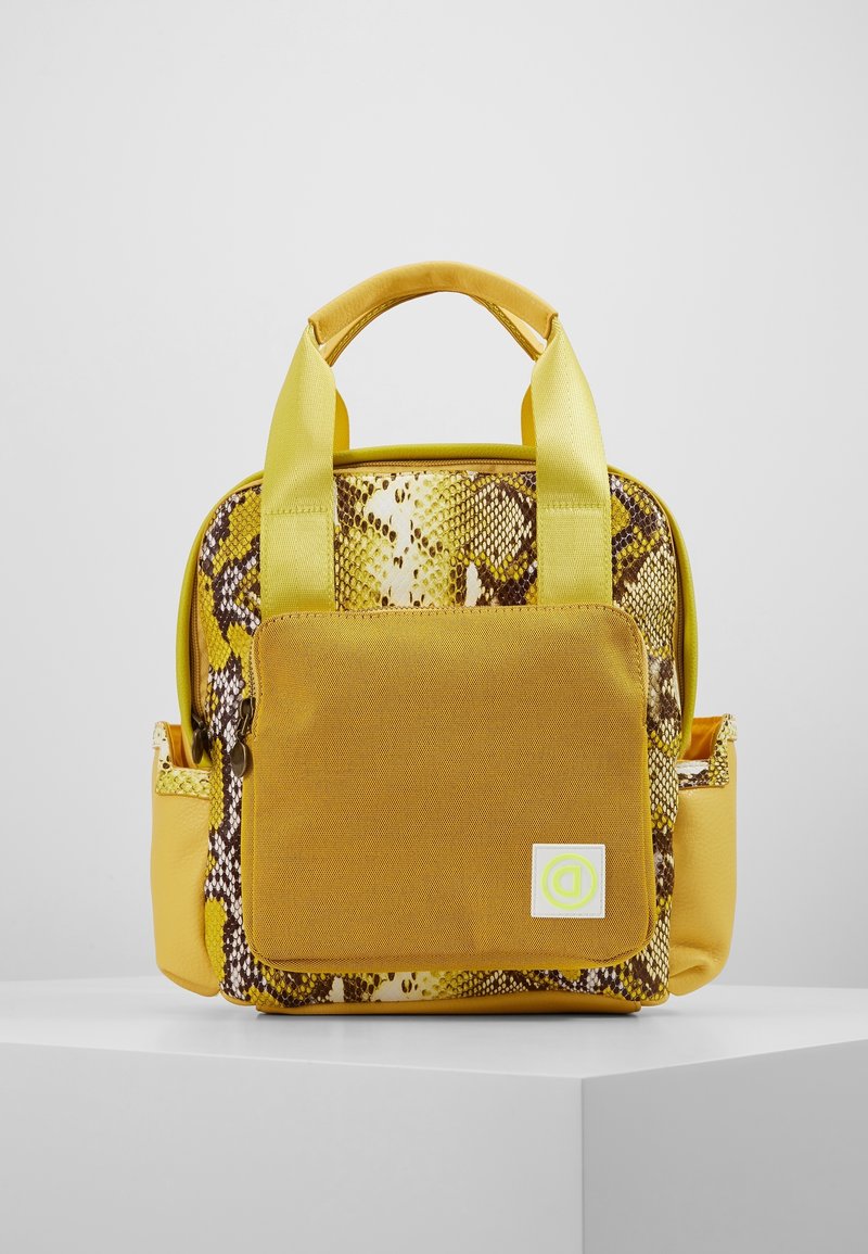 Mochila amarilla con un reverso de patrón de serpiente, que cuenta con un bolsillo frontal, dos asas superiores y una textura suave.