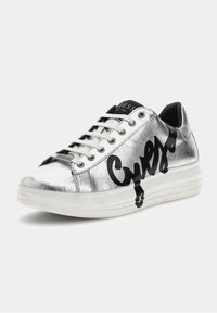 Baskets métalliques argentées avec logo "Guess" noir, lacets blancs, semelle en caoutchouc, et design basse. Texture lisse avec un éclat subtil.