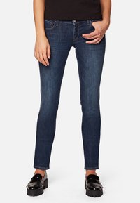 Jeans skinny azul oscuro en denim con una textura suave, que cuentan con bolsillos frontales, una cremallera y un detalle de costura sutil.