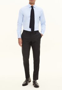 Himmelblaues Hemd kombiniert mit dunkelgrauen, maßgeschneiderten Hosen. Das Hemd hat einen Kentkragen und das Outfit wird mit schwarzen Schuhen abgerundet.