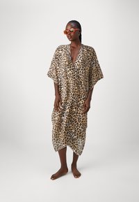 Cubierta de leopardo con escote en V, mangas cortas y una tela ligera y transparente. Presenta un corte holgado y un dobladillo asimétrico.
