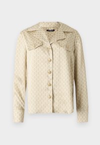 Béžová košeľová bunda s veľkým golierom, zapínaním na gombíky a celoplošným bielym vzorom loga. Dlhé rukávy s gombíkovými manžetami, hladká textúra látky.