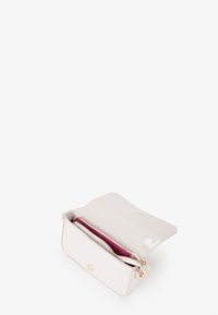 Cartera de imitación piel blanca brillante con cierre de cremallera, que presenta un interior rosa y detalles en dorado. Forma rectangular compacta.