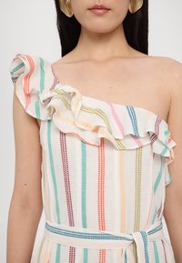 Vestido de um ombro com padrão de riscas coloridas em tons pastel. Acabamento com babados e cinto a condizer. Feito de tecido leve.