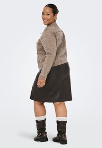 Brūns leoparda raksta džinsu jaka, melna ādas A-veida svārki un melni augstās zābaka ar zeķēm. Ikdienišķs, pieguļošs stils ar redzamu aparatūru.