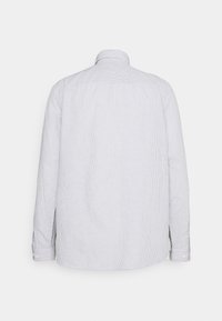 Chemise blanche à manches longues boutonnée avec fines rayures verticales grises, vue de dos sur un fond blanc uni.